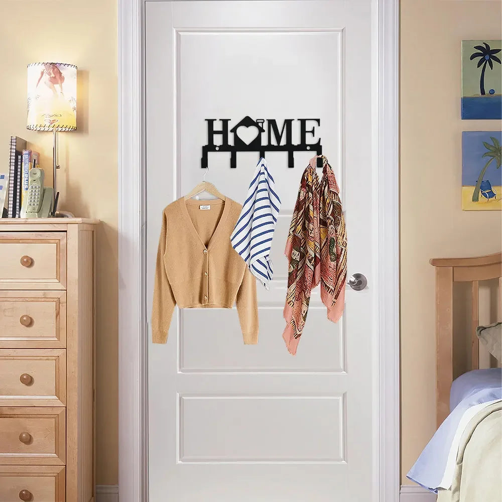 A white door features a black sign with the word HOME and hooks for hanging clothing.