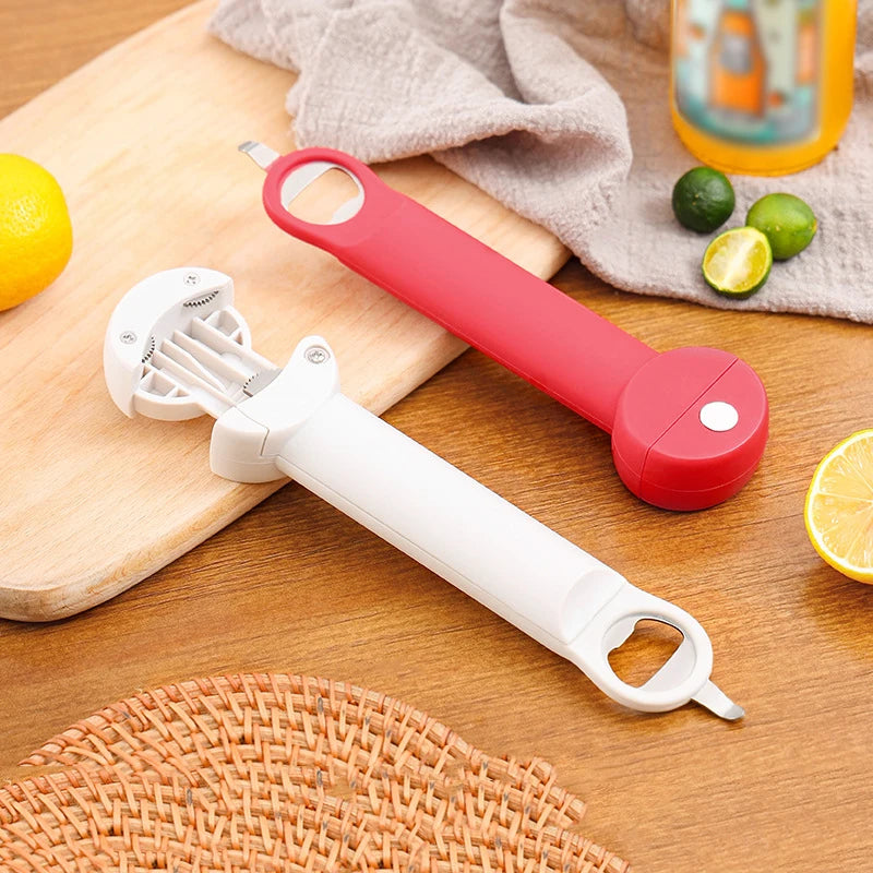 A white ergonomic jar and bottle opener set with a red handle rests on a wooden board next to a cloth and citrus fruits.