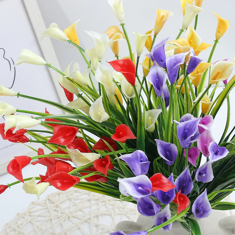 A vibrant bouquet of artificial calla lilies in shades of white, yellow, red, and purple.