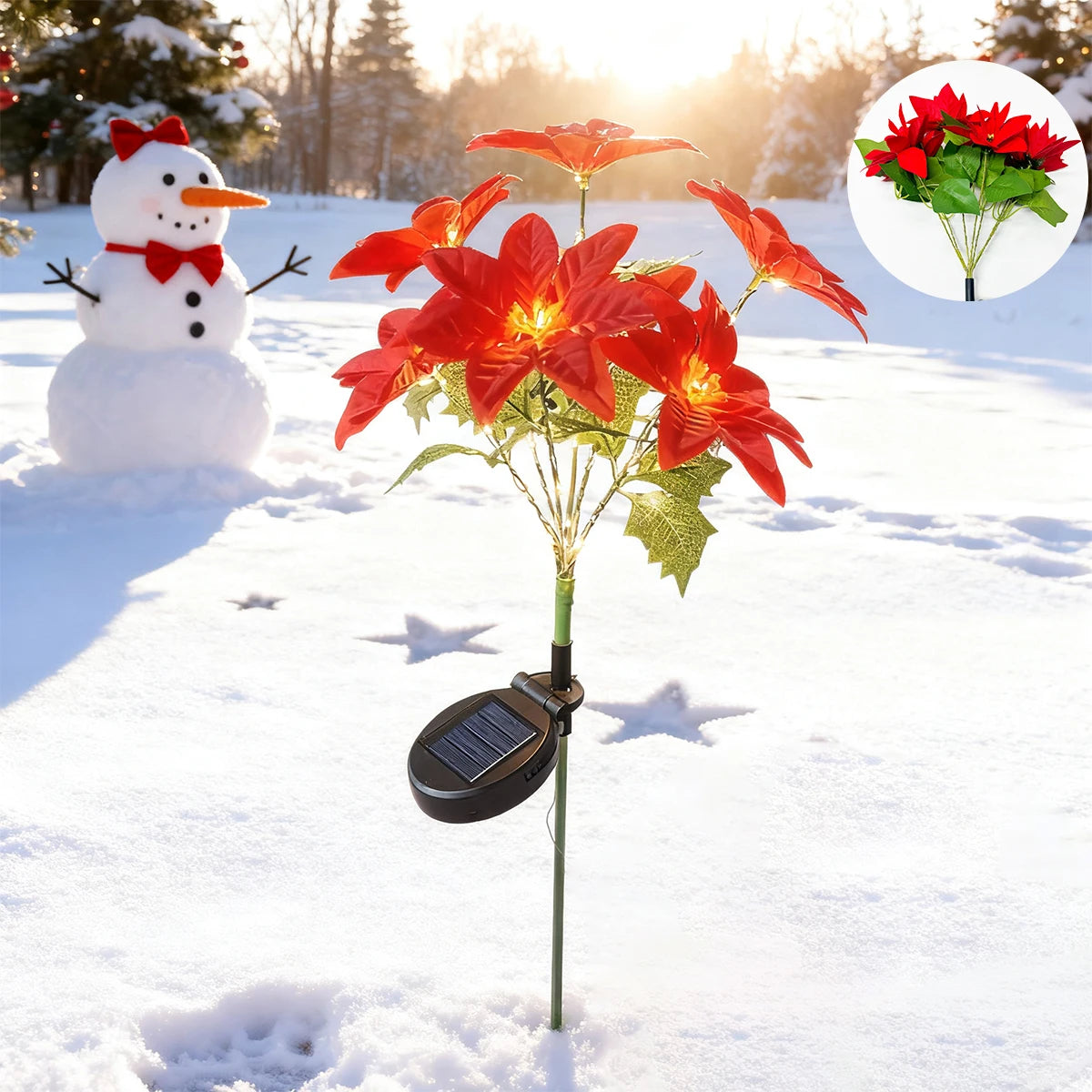 A solar-powered poinsettia garden light with bright red flowers growing in a snowy outdoor setting.