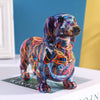 A colorful resin figurine of a dachshund dog standing on a white box.