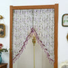 A sheer lace door curtain with purple floral embroidery and tassels hanging in a wooden frame.