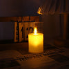 A glass candle holder with a flickering yellow flame illuminates a piece of paper.