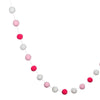 A string of colorful felt balls in pink and white creating a decorative garland