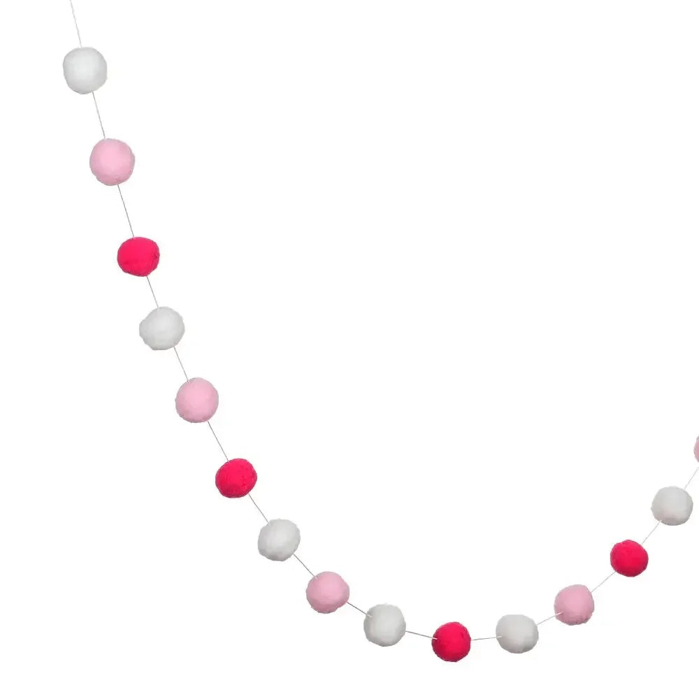 A string of colorful felt balls in pink and white creating a decorative garland