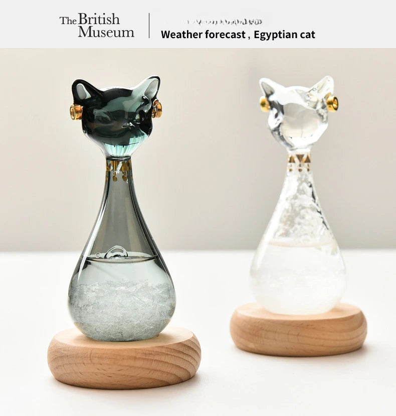 A glass bottle shaped like an Egyptian cat with a green body and gold accents, displayed on a wooden base.