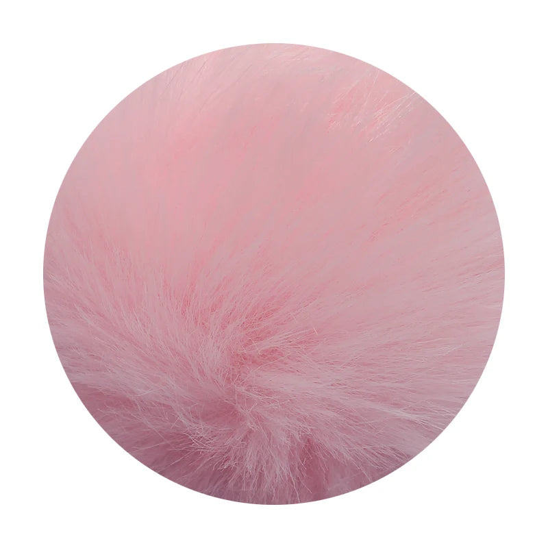 A round pom pom made of pink faux fur with a silver chain attached.