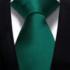 A dark emerald green silk necktie tied in a knot against a black suit jacket.