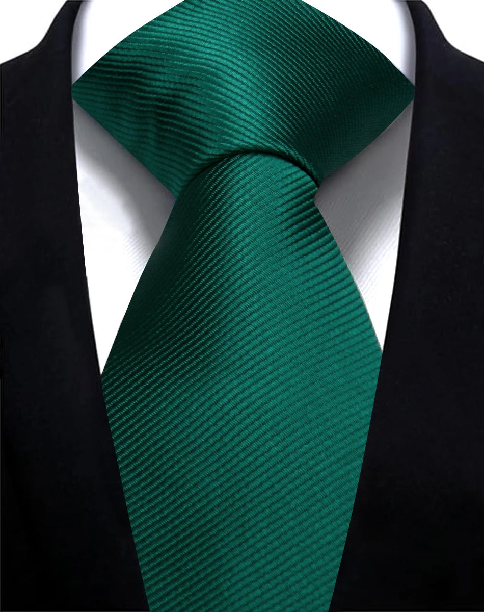 A dark emerald green silk necktie tied in a knot against a black suit jacket.