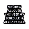 Black enamel pin with white text that reads NO CRISIS ALLOWED THIS WEEK MY SCHEDULE IS ALREADY FULL