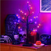 A dark tree silhouette illuminated by glowing purple LED lights on a wooden surface.