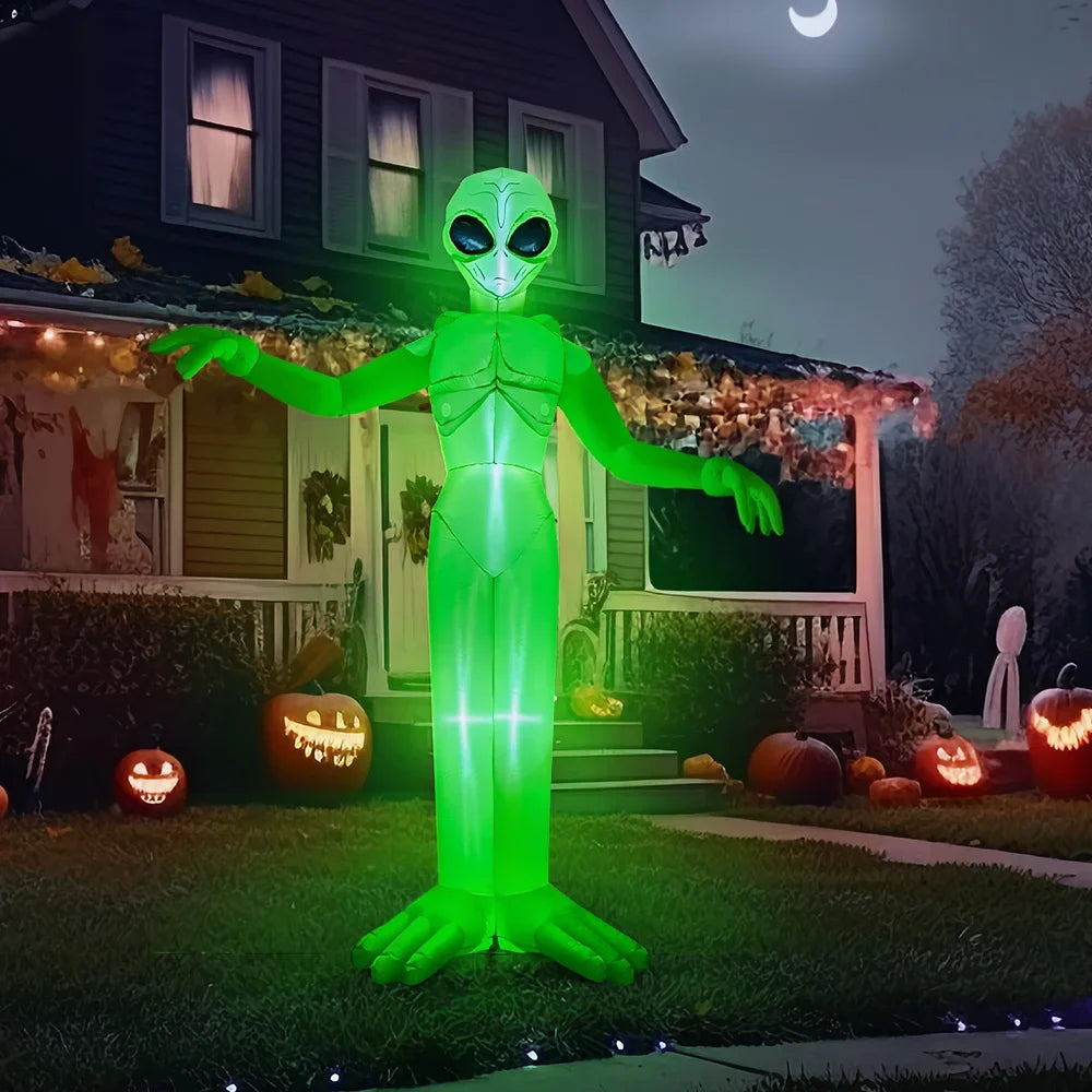 A glowing green inflatable alien decoration standing in a front yard at night for Halloween
