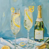 A glass of sparkling wine and lemon slices are displayed on a white cloth with a bottle in the background.