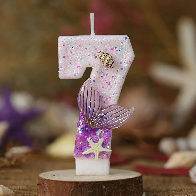 Pink birthday candle shaped like the number 7 decorated with glitter and a purple starfish and leaf