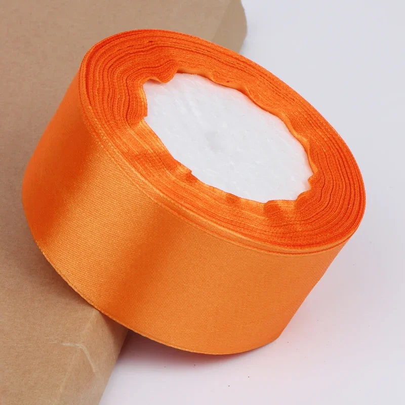 Roll of bright orange satin ribbon with a white center for crafts and gift wrapping