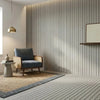 A modern interior featuring a light gray wall with vertical wood grain paneling, a blue armchair, and a light wooden shelf.