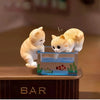 Three adorable cat figurines are placed on a glass fish tank decorated with aquatic plants and fish.