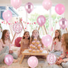 Six children sitting on the floor surrounded by pastel pink and white latex balloons with metallic confetti accents
