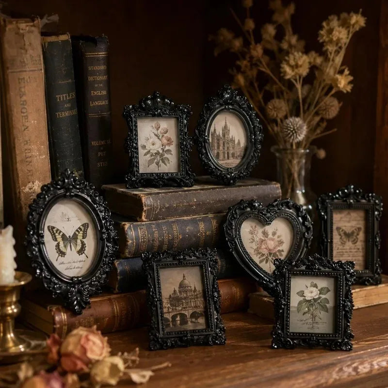 A collection of vintage resin mini picture frames displayed on a wooden surface with old books and dried floral elements.