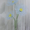 A light blue artificial silk poppy flower displayed on a green stand against a white background.