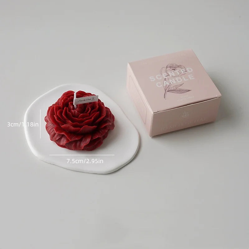 A handcrafted rose-shaped scented candle in red is displayed next to its pink box.