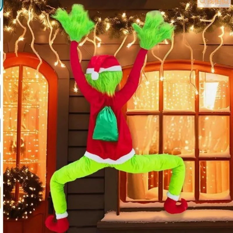 A person dressed as a green monster wearing a red sweater and lime green pants stands in front of a decorated window.