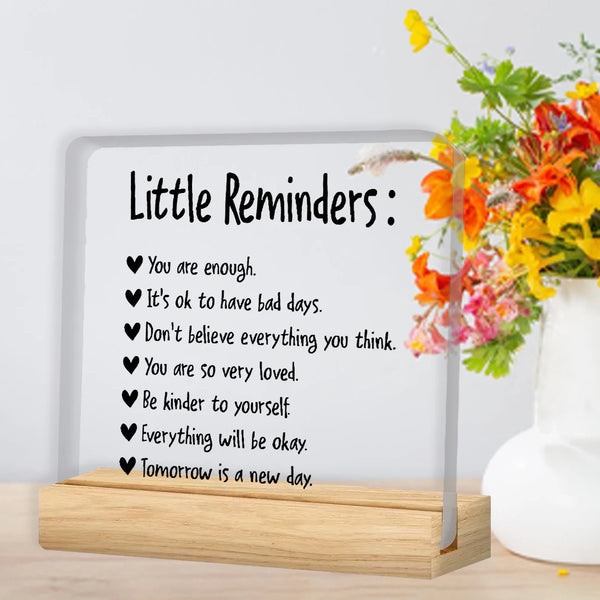 A clear acrylic desk plaque with a list of positive reminders like You are enough and Be kinder to yourself.