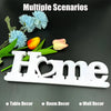 White wooden cutout letters spelling Home with blue flowers and a yellow rose in a decorative arrangement