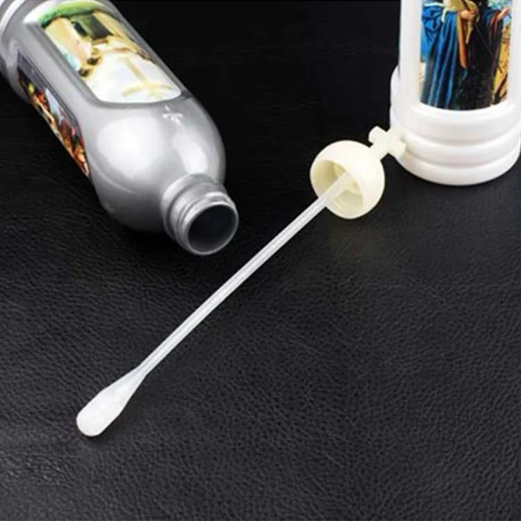 A glow-in-the-dark holy water bottle and a glass dropper are shown on a dark surface.