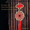 Ten copper coins and a plum blossom peace talisman pendant with a Chinese knot hanging from bamboo rods.