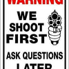 A white warning sign with red text instructing to shoot first and ask questions later.