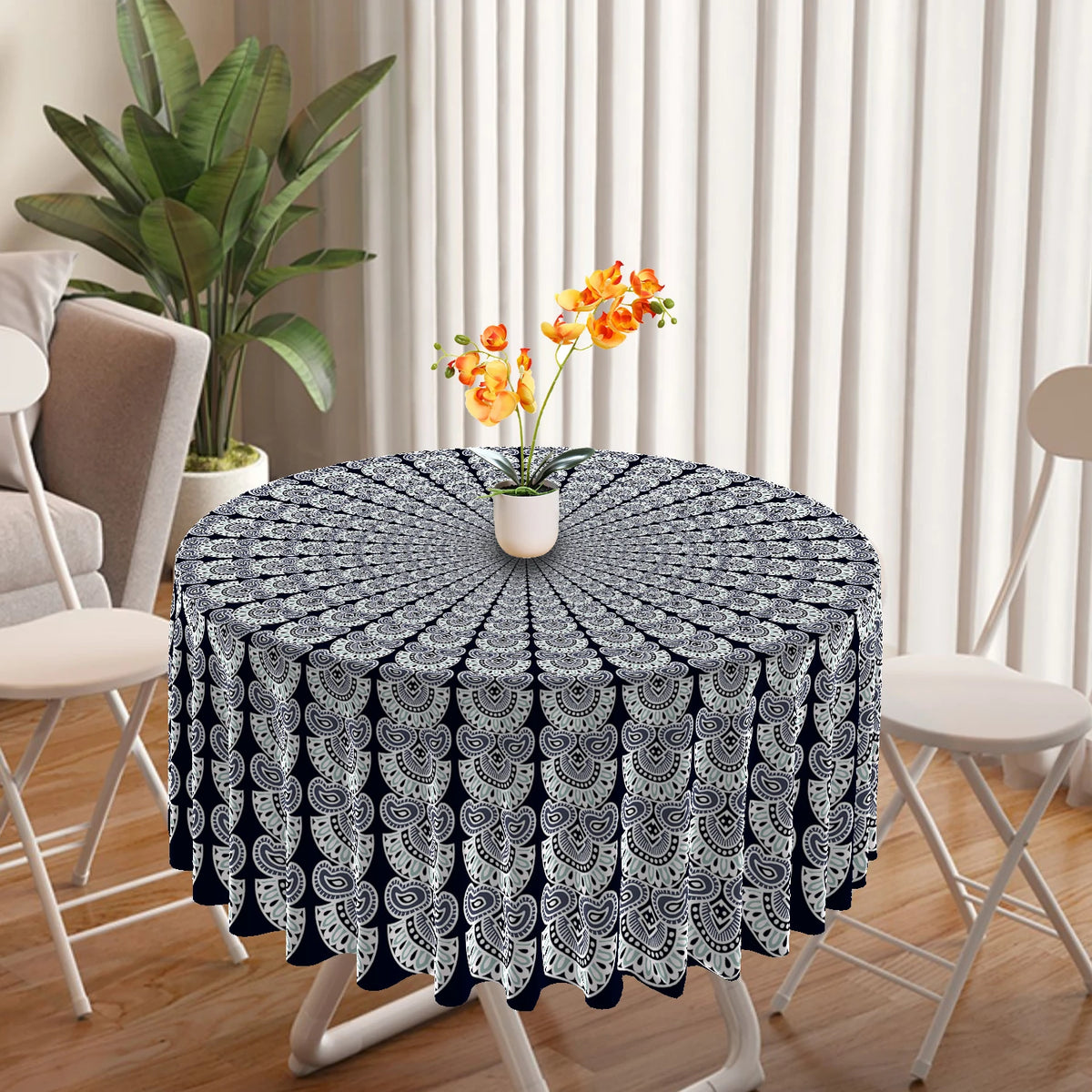 A round table covered with a black and white bohemian peacock mandala tablecloth, set in a bright room.