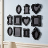 A collection of black, ornate, European-style resin wall decor pendants displayed on a light blue wall.