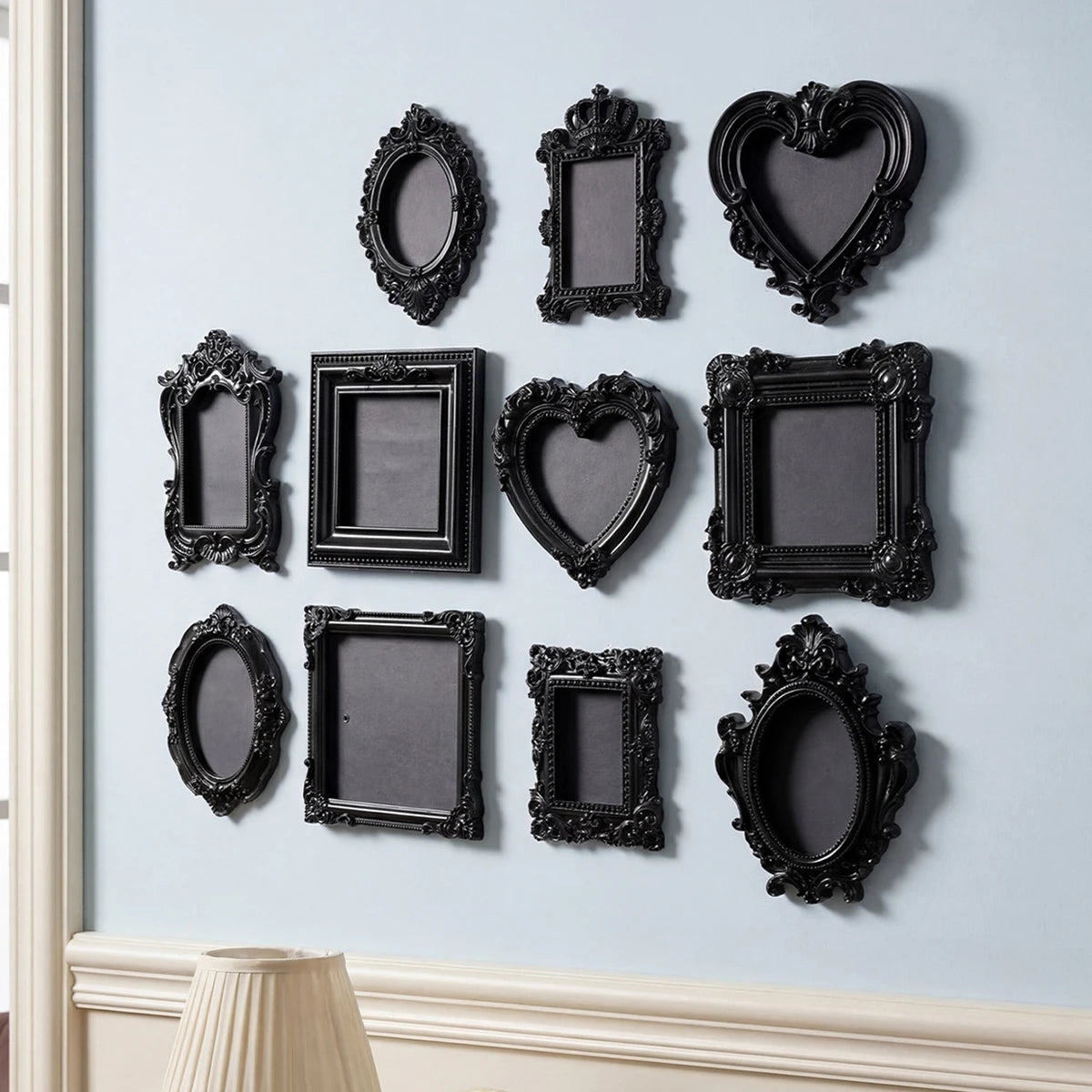 A collection of black, ornate, European-style resin wall decor pendants displayed on a light blue wall.
