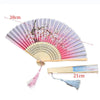A vintage silk folding fan with pink and white oriental patterns, shown open and closed.