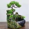 A resin desktop fountain featuring a mossy rock landscape with a small tree and flowing water.