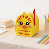 A yellow magnetic mailbox cover shaped like a duck, with the text Leave a Duck Take a Duck, resting on a light surface.