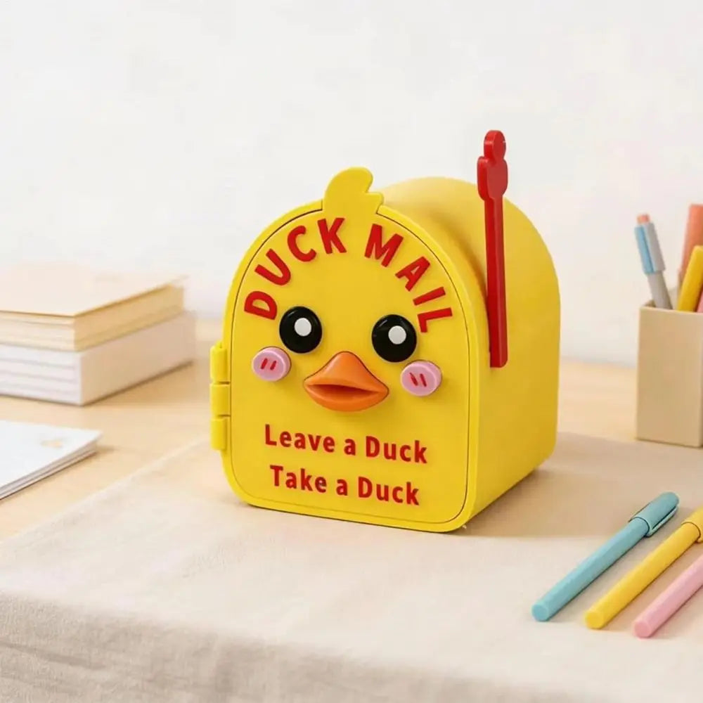 A yellow magnetic mailbox cover shaped like a duck, with the text Leave a Duck Take a Duck, resting on a light surface.