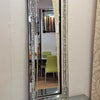 A silver crystal beveled wall mirror reflecting a room with green furniture.