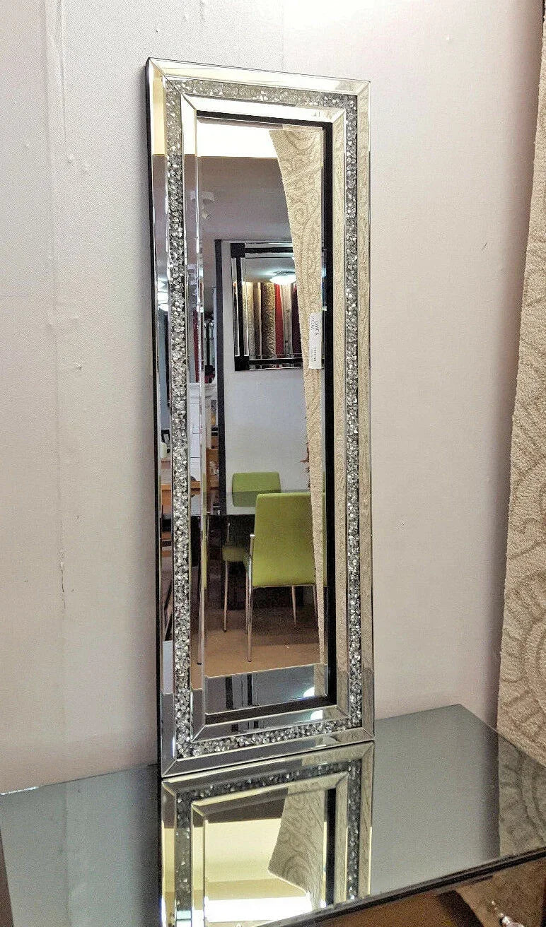 A silver crystal beveled wall mirror reflecting a room with green furniture.