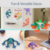 A collection of colorful frog fridge magnets and a 3D printed frog decoration displayed on a white surface.