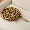 A realistic brown and yellow patterned snake plush toy coiled on a white surface.