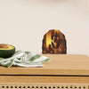 A wooden surface holds an avocado, a green striped cloth, and a decorative wall decal featuring a mouse in a wooden frame.
