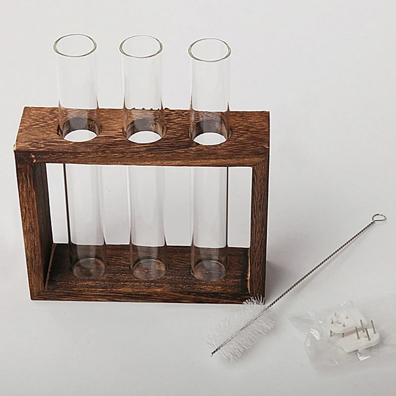 A wooden planter box holds three glass test tube vases for hydroponic growing.
