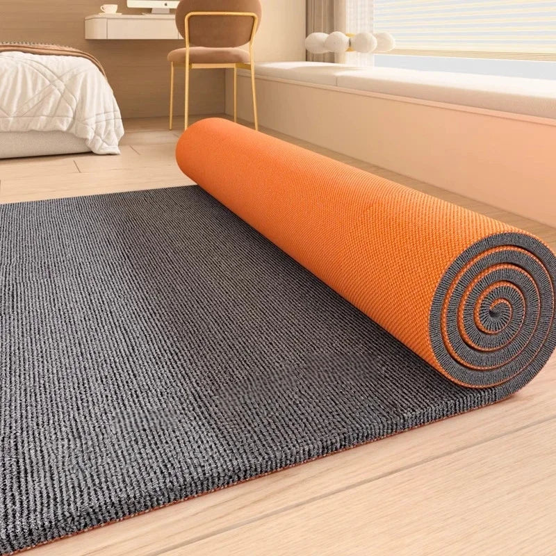 Orange cylindrical artificial grass carpet rolled out on a wooden floor.