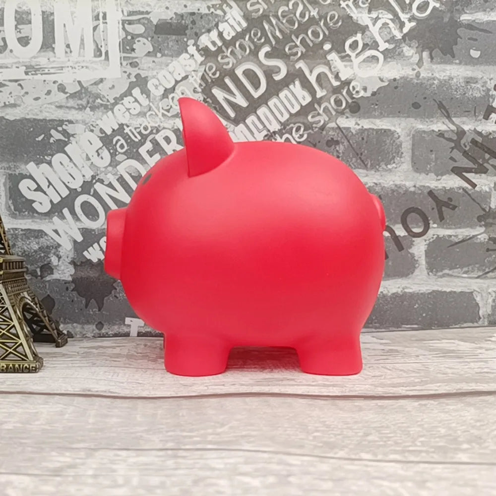 A bright red piggy bank shaped like a pig sitting on a light wooden surface.