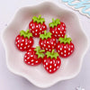 Five bright red strawberry resin flatback charms with green leaves arranged on a white ceramic dish.