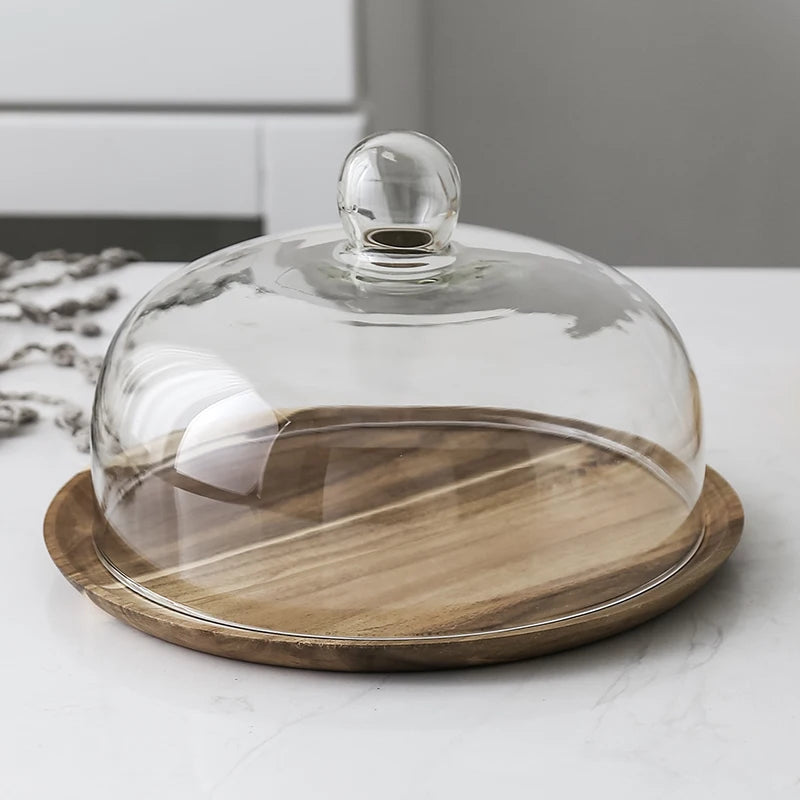 Solid acacia wood cake tray with a glass dome cover resting on a white surface.