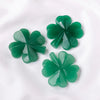 A cluster of green Aventurine quartz four-leaf clover crystal statues on a white background.