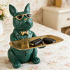 A decorative green bulldog figurine wearing sunglasses and a bow tie holding a gold tray with keys.